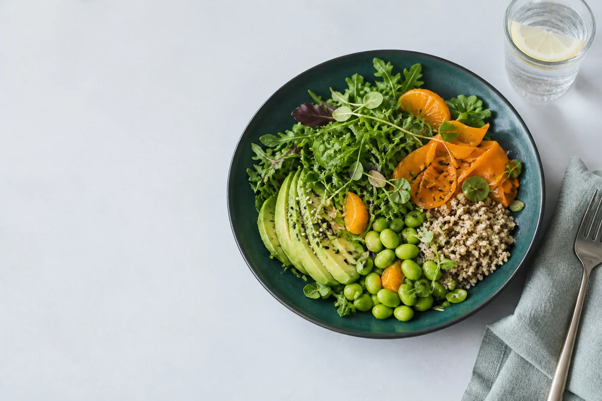 Plato de verduras, aguacate y granos sobre una mesa clara